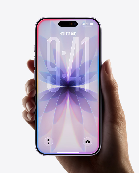 iPhone 17을 들고 있는 손. 전면 화면 디스플레이, Liquid Glass 테두리가 표시된 잠금 화면이 보입니다