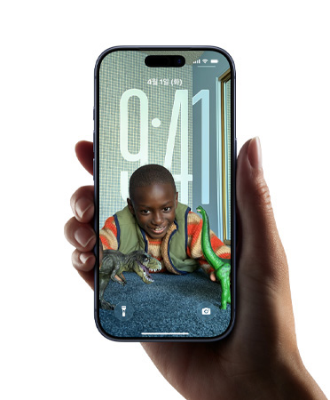 잠금 화면의 이미지에 맞춰 시간 형태가 유동적으로 변하는 새로운 Liquid Glass 디자인을 보여주는 iPhone 기기를 쥔 손