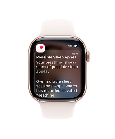 Apple Watch Series 11 z kopertą z aluminium w kolorze różowego złota, pasek sportowy w kolorze łagodnego różu, rozwinięte powiadomienie o bezdechu sennym, prawy bok urządzenia, pokrętło Digital Crown