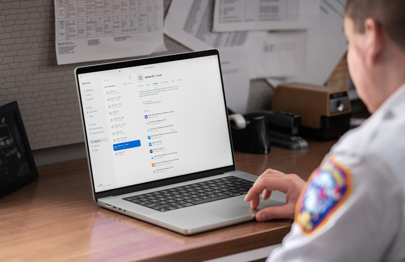 Un responsable du service des pompiers est assis à son bureau et utilise un MacBook avec Apple Business Essentials affiché à l'écran