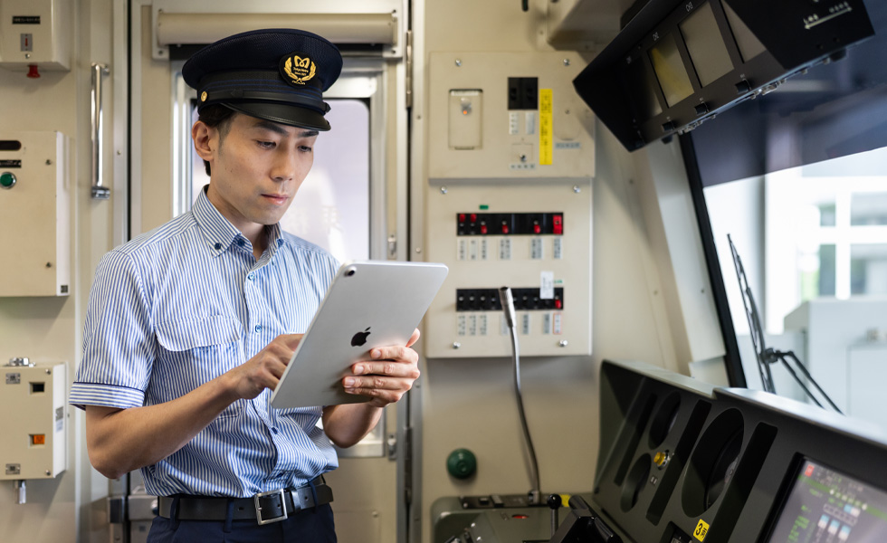 Người lái tàu tương tác với iPad khi đứng trong buồng lái sáng ngời của chuyến tàu mình điều khiển.