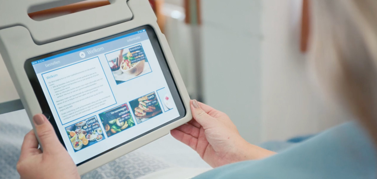 Một bệnh nhân đang nhìn vào màn hình iPad khi ngồi trên giường bệnh.